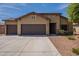 Single-story home with a three-car garage, complemented by desert landscaping and stone accents at 17531 W Fetlock Trl, Surprise, AZ 85387