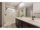 Bathroom featuring a double sink vanity with dark wood cabinets and a glass-enclosed shower with tiled floors at 17531 W Fetlock Trl, Surprise, AZ 85387