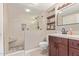Stylish bathroom with a glass enclosed shower, built-in shelves, dark cabinets, and a granite countertop at 18626 N 130Th Ave, Sun City West, AZ 85375