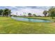 Scenic pond view on the golf course with lush green grass, a decorative fountain, and mature trees at 18626 N 130Th Ave, Sun City West, AZ 85375