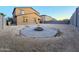 Backyard with a circular stone patio, a fire pit, and ample space for outdoor activities at 19954 W Moonlight Path, Buckeye, AZ 85326