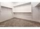 An empty walk-in closet with carpeted floors and ample shelving for storage at 19954 W Moonlight Path, Buckeye, AZ 85326