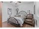 Comfortable bedroom with wood-look ceramic tile flooring, a metal bedframe, a chair and neutral wall color at 2466 E Aris Dr, Gilbert, AZ 85298