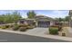 Lovely home features a two-car garage, desert landscaping with vibrant flowers, and a charming front patio with a bright yellow umbrella at 2466 E Aris Dr, Gilbert, AZ 85298