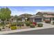 An inviting home boasts a two-car garage, desert landscaping adorned with colorful flowers, and a cozy front patio with a bright umbrella at 2466 E Aris Dr, Gilbert, AZ 85298