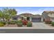 Charming home with a two-car garage, low-maintenance desert landscaping with colorful flowers, and a cozy front patio with a yellow umbrella at 2466 E Aris Dr, Gilbert, AZ 85298