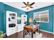 Office with blue accent wall, ceiling fan, built-in bookcase and wood laminate flooring at 2551 W Sawtooth Way, San Tan Valley, AZ 85144