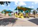 Community playground featuring slides, climbing structures, and shade canopies, ideal for recreation at 38065 W Frascati Ave, Maricopa, AZ 85138