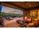 Cozy patio with lounge chairs, dining set, fire pit, and sunset views over the desert landscape at 41731 N Rolling Green Way, Anthem, AZ 85086