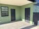 A covered patio with gray tile flooring, two access doors, and painted green stucco walls offers versatile outdoor space at 4602 N 47Th N Ave, Phoenix, AZ 85031