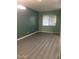 An empty room with hardwood floors with light-green painted walls and one window at 4722 S 238Th Ln, Buckeye, AZ 85326