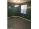 A modern empty room with a hardwood floor, a modern light fixture, and a window at 4722 S 238Th Ln, Buckeye, AZ 85326