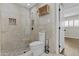 Tiled bathroom showcasing a glass-enclosed shower with pebble flooring, toilet, and adjacent bedroom at 5525 E Thomas Rd # K16, Phoenix, AZ 85018