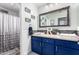 Bathroom featuring navy vanity, double sinks, and a shower with glass door at 597 S 221St Dr, Buckeye, AZ 85326