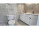 Bright bathroom featuring a dual sink vanity with white cabinets and stone-look tile surround at 6104 W Marconi Ave, Glendale, AZ 85306
