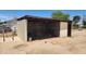Concrete block storage shed with a dark wooden door and a pile of wood inside at 6104 W Marconi Ave, Glendale, AZ 85306