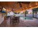 This covered patio includes a swimming pool, a dining table, and a ceiling fan at 6901 E Oak St, Scottsdale, AZ 85257