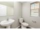 Powder room featuring a pedestal sink and toilet, with a window providing natural light at 823 E Agua Fria Ln, Avondale, AZ 85323