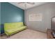 A bedroom with neutral carpet, gray walls, green futon, window, and mounted flatscreen TV at 872 E Saratoga St, Gilbert, AZ 85296