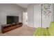 A cozy carpeted bedroom with a flatscreen TV, wood entertainment stand and closet at 872 E Saratoga St, Gilbert, AZ 85296