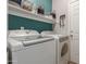Bright laundry room with modern washer and dryer, storage shelves, and convenient key rack near the entry door at 872 E Saratoga St, Gilbert, AZ 85296