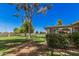 Serene backyard featuring lush green lawn, mature trees and manicured shrubs creating a park-like setting at 10913 W Caron Dr, Sun City, AZ 85351