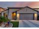 Charming home exterior with beautiful desert landscaping, artificial turf and warm lighting at dusk at 11829 W Patrick Ln, Sun City, AZ 85373