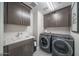 Well-lit laundry room with sleek cabinetry, modern washer, and dryer at 12233 W Caraveo Pl, Peoria, AZ 85383