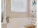 Relaxing bathroom featuring a soaking tub with tile surround, complemented by beach-themed decor, and large window at 17229 N 51St Dr, Glendale, AZ 85308