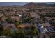 Expansive aerial view of a neighborhood at dusk featuring beautiful homes, street lights, and mountain views at 21228 E Excelsior Ave, Queen Creek, AZ 85142