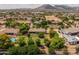 An aerial view of a home with a large backyard, lush landscaping, and mountain views at 21228 E Excelsior Ave, Queen Creek, AZ 85142