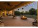 Covered back patio featuring a brick paver floor, hanging plants, a fire pit, and string lights at 21228 E Excelsior Ave, Queen Creek, AZ 85142