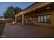 Outdoor back patio with a brick paver floor, string lights, and a fire pit surrounded by landscaping at 21228 E Excelsior Ave, Queen Creek, AZ 85142