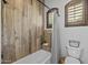 Bathroom featuring wood-look tile, built-in niche, and a shower-tub combo with a window at 21228 E Excelsior Ave, Queen Creek, AZ 85142