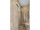 Shower featuring stone pebble floor, gray wood-look tiled walls, and built-in shelving at 21228 E Excelsior Ave, Queen Creek, AZ 85142