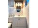 Bathroom with white vanity, white tiled walls, decorative lighting and artwork at 2335 W Campus Dr, Phoenix, AZ 85015