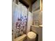 Cozy bathroom featuring a floral shower curtain, tiled walls, and functional storage space at 2335 W Campus Dr, Phoenix, AZ 85015