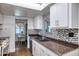 Bright kitchen with white cabinetry, mosaic backsplash, and eat-in dining area at 2335 W Campus Dr, Phoenix, AZ 85015