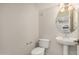 Half bathroom with white toilet and pedestal sink, features oval mirror reflecting the kitchen at 3150 E Beardsley Rd # 1091, Phoenix, AZ 85050