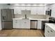 Modern kitchen with stainless steel appliances, white cabinetry, quartz countertop, and wood flooring at 3517 E Blanche Dr, Phoenix, AZ 85032