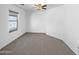 A simple carpeted bedroom illuminated by a ceiling fan and a well-lit window at 40168 W Sanders Way, Maricopa, AZ 85138