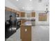Open kitchen boasts an island with breakfast bar, neutral counters, and modern black appliances at 40168 W Sanders Way, Maricopa, AZ 85138