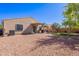 Backyard with rock landscaping, covered patio, green grass area, and mature trees at 42406 W Posada Dr, Maricopa, AZ 85138