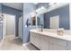 This bathroom features blue walls, white cabinets, and a well-lit vanity area for a fresh and clean feel at 42406 W Posada Dr, Maricopa, AZ 85138