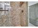 Close-up of the remodeled shower with decorative stone walls and bronze fixtures at 5281 W Quail Ave, Glendale, AZ 85308