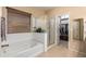 Bathroom with a luxurious tub, glass-enclosed shower, and access to the walk-in closet at 5735 S Cloverdale Ln, Gilbert, AZ 85298