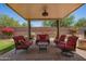 Comfortable covered patio with red cushioned seating, ceiling fan, and landscaped backyard at 5735 S Cloverdale Ln, Gilbert, AZ 85298