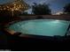Backyard pool, lit by string lights, offers a refreshing escape under a shaded umbrella in the evening at 5735 S Cloverdale Ln, Gilbert, AZ 85298