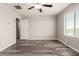 A spacious bedroom featuring new hardwood flooring, a ceiling fan, and a sunlit window at 8208 W Albeniz Pl, Phoenix, AZ 85043