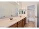 Bright bathroom features a double sink vanity with a large mirror, complemented by tile flooring and modern fixtures at 8766 W Hayward Ave, Glendale, AZ 85305